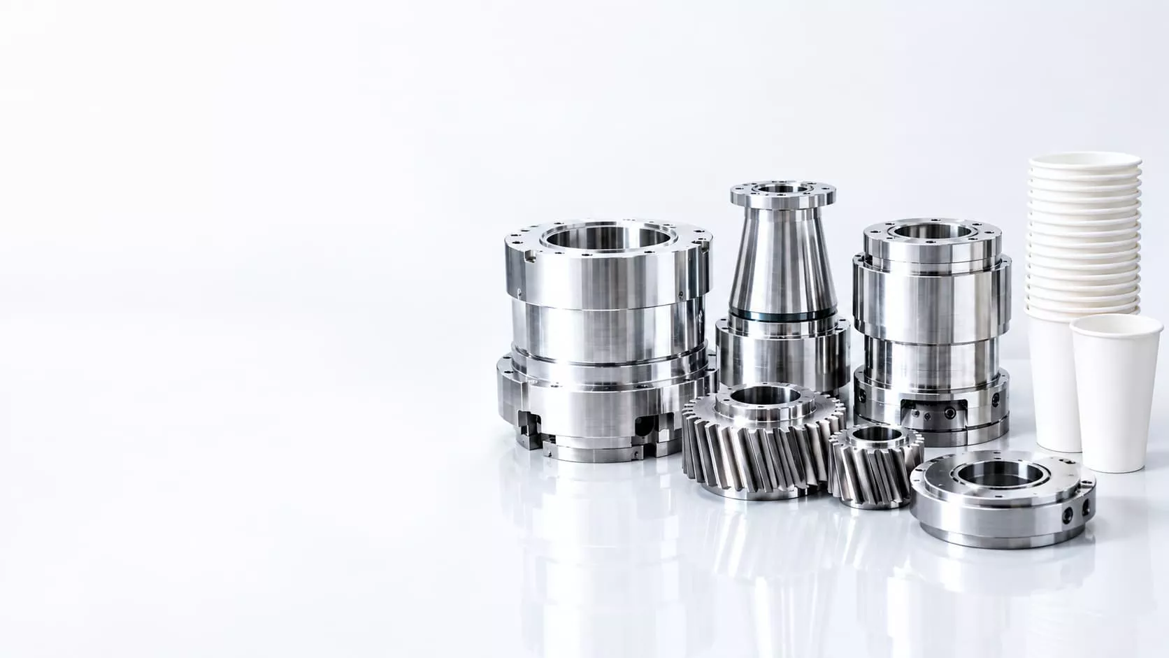 Industrial mechanical components including precision machined metal parts, gears, and bearings displayed on a white