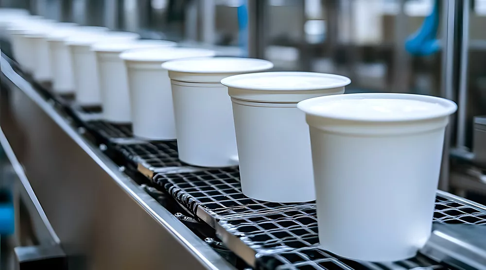 White sealed plastic cups on an industrial production line conveyor